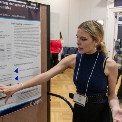 A student pointing to a poster at the Undergraduate Research Symposium
