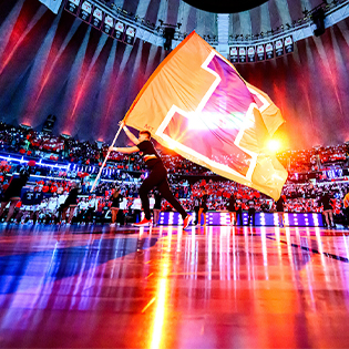 A cheerleader runs a Block I flag across the State Farm Center court