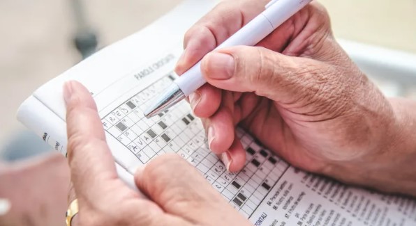 elderly person's hands shown completing a crossword puzzle. Yunio Baro Gomez / Getty Images