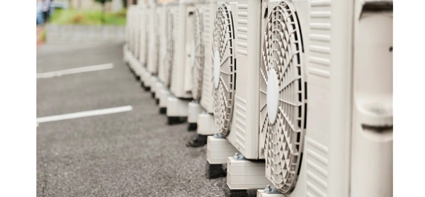 a line of air conditioners operate while sitting on black pavement. Photo from Getty images