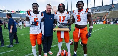 Illinois coach and three players pose with the Cannon Trophy