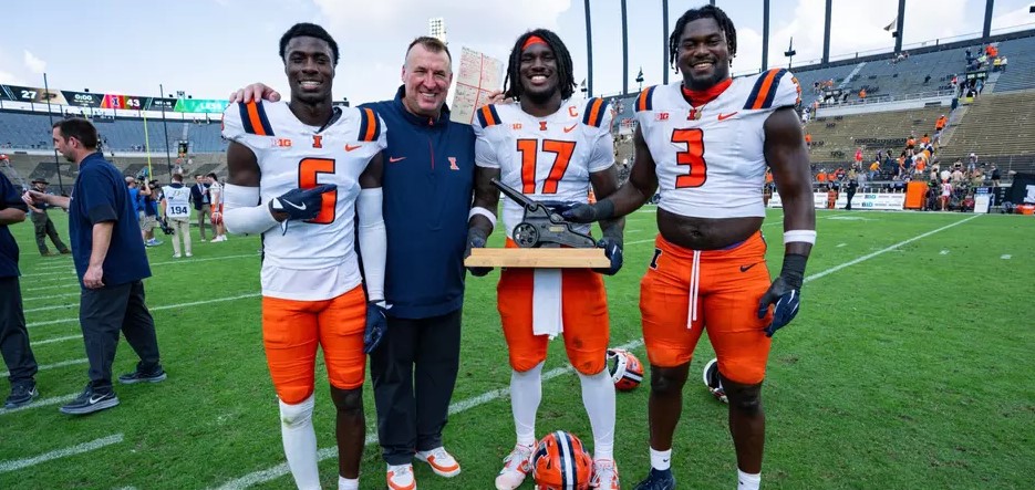 Illinois coach and three players pose with the Cannon Trophy