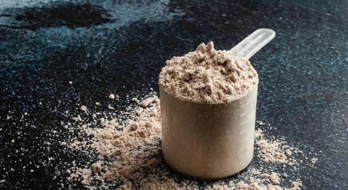 stock image of protein powder in a measuring cup.