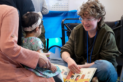 Someone from the Urbana Free Library reads to a child and her mother during the April 24 International Families Celebration inside the Orchard Downs Community Center.