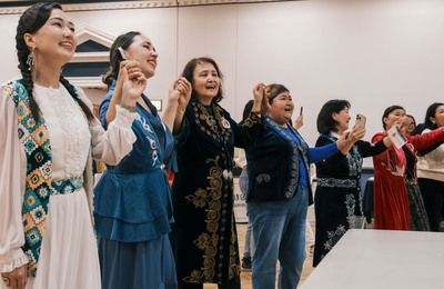 Several Bolashak Scholars join hands and sing along with a performance during the 2024 Travel Around the World event.