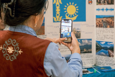 A Bolashak Scholar snaps a picture of the Kazakhstan table display during the 2024 Travel Around the World event.