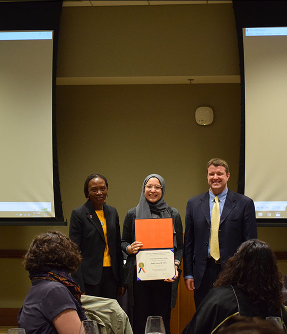 Doha Amer poses on stage holding an award