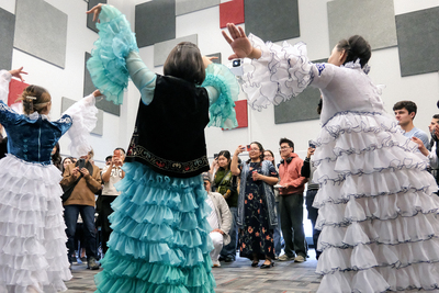 Several Bolashak scholars dance in traditional dress while an audience records and watches.