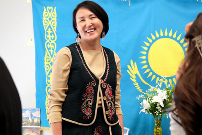 Shynar Imangaliyeva, GET program coordinator, smiles at the camera as she stands in front of the Kazakhstan flag.