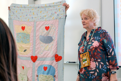 Jennie Burden stands next to and talks about a baby quilt she made for her daughter, Kathryn, during a Jan. 7 workshop inside the Siebel Center for Design.