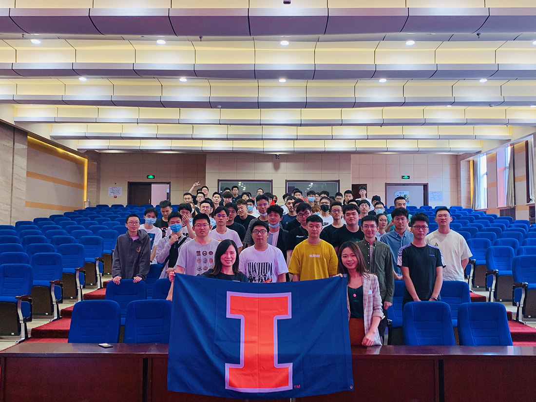 Faculty and students pose at orientation holding the Illinois banner