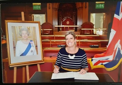 Melissa Belcher smiles while signing a guest registry in a historic UK government chamber