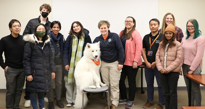 Members of GET and IEI pose for a photo with Kirby, a therapy K-9, and UIPD Detective Tara Hurless.