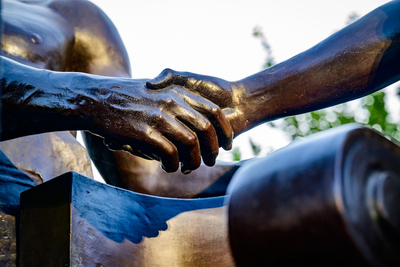 Behind Alma Mater are figures of a woman representing “learning” and a man depicting “labor” joining hands. Together they symbolize the University’s motto, “Learning and Labor.”  Alma Mater, the beloved bronze mother figure that has greeted generations of University of Illinois students, graces the entry way to the campus. Alma Mater, which was created by sculptor Lorado Taft, is a 10,000-pound statue depicting a mother-figure wearing academic robes, bearing a plaque that reads, "To thy happy children of the future, those of the past send greetings.” Photo taken at the University of Illinois Urbana-Champaign on Tuesday, Sept.  30, 2025.  (Photo by Fred Zwicky / University of Illinois Urbana-Champaign)
