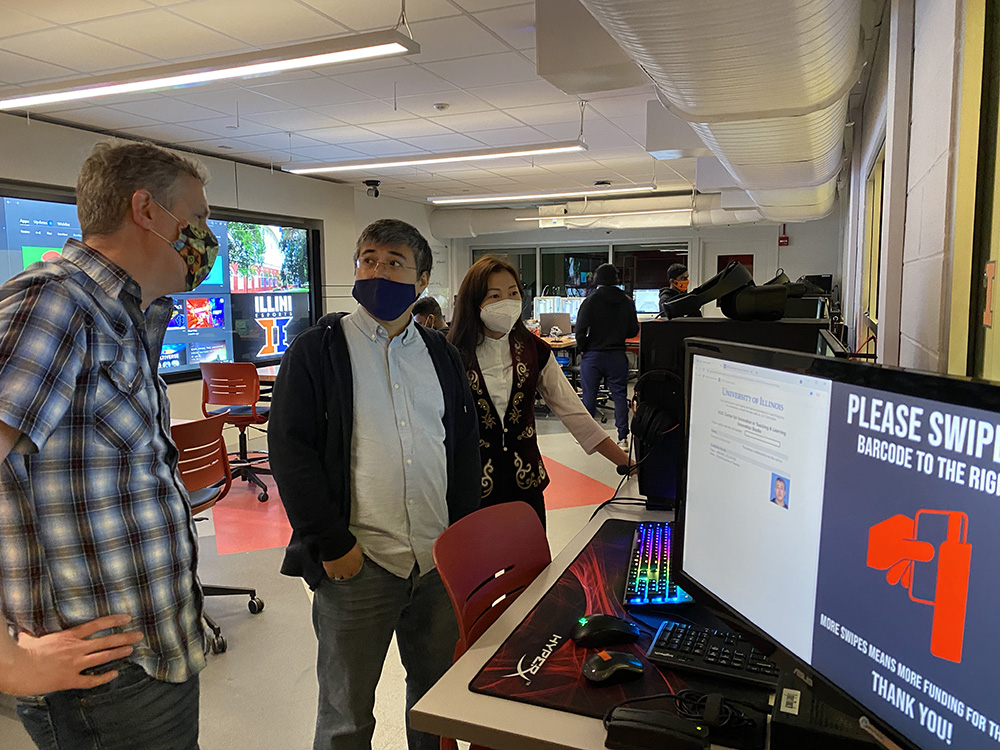 Aseel Aryn and Kaunysh Abeshev are talking to another faculty in a computer room