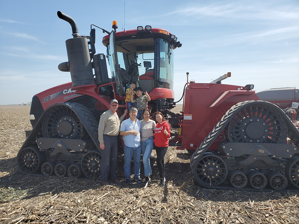 Aseel Aryn, Kaunysh Abeshev, and family pose in front of a tractor