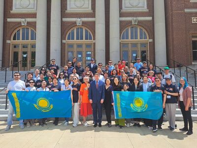Bolashak fellows from Kazakhstan pose for a photo with the Kazakhstani flag and with members of Global Education and Training in front Foellinger Auditorium in July 2024.
