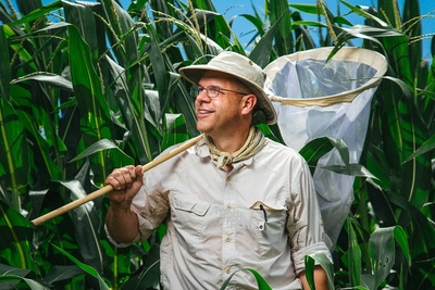 Joseph Spencer is shown in a cornfield carrying a net over his shoulder.