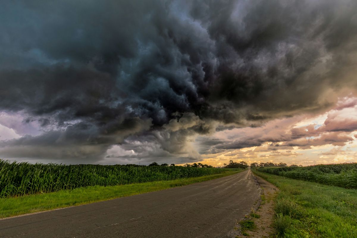 Storm clouds over a country road and farm fields.