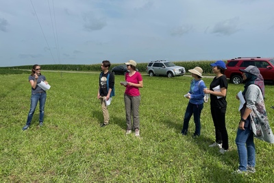 Allison Goodwell stands to the left of a group of students in a field