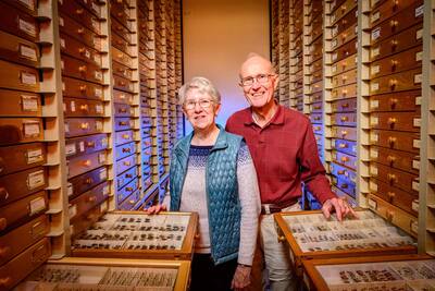 Bill and Cindy Ruesink stand between shelves of insect drawers.