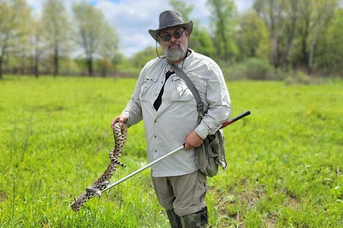 Michael Dreslik holds a snake in the field.