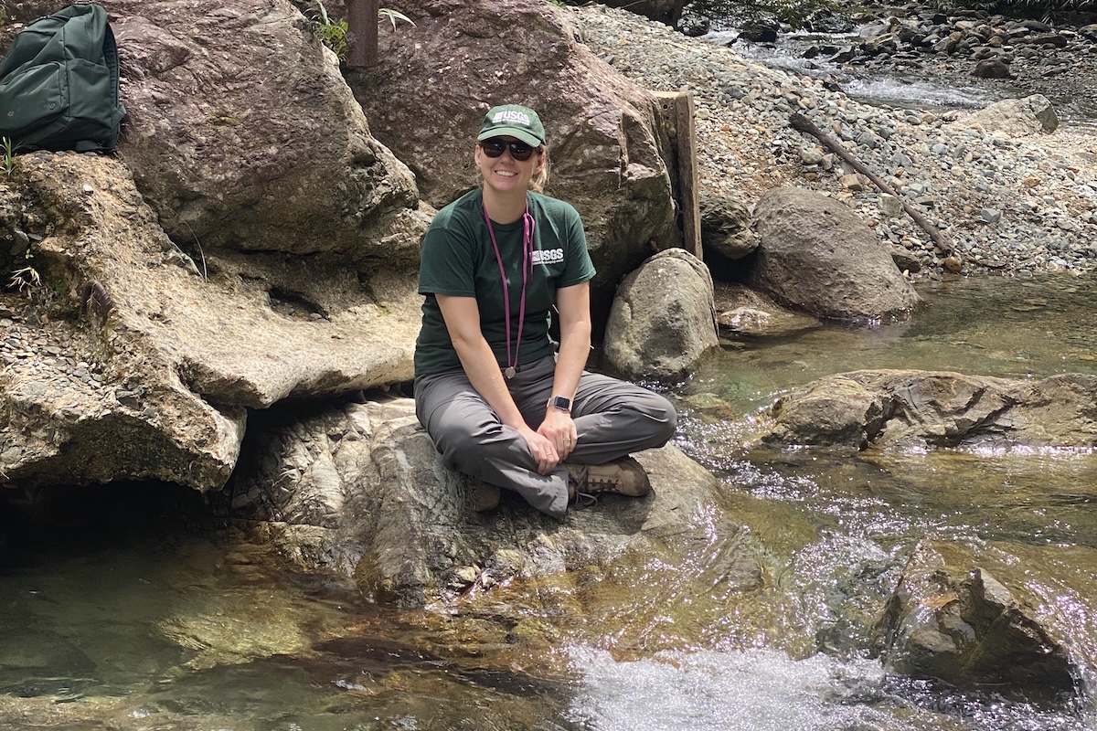 Jenna Shelton sits by a river during a field research trip.