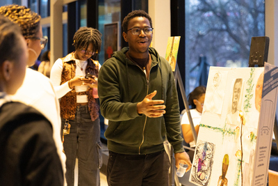 a man standing into front of an art piece while two others look on