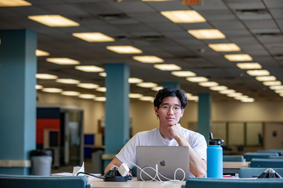 a student sits facing a laptop in a large room