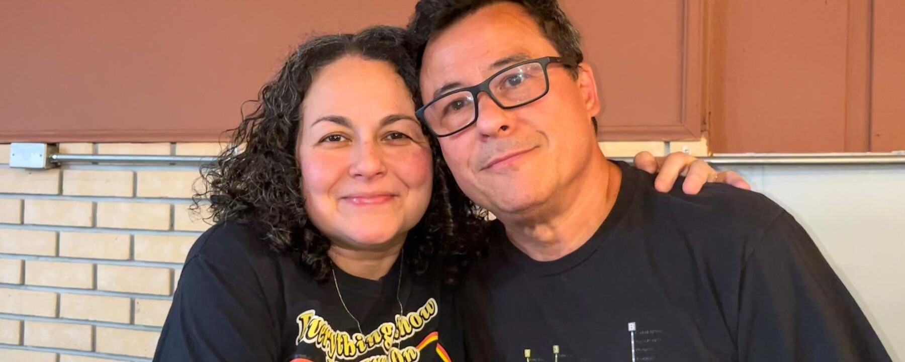 Dr. Evelyn Figueroa, wearing a black T-shirt, and her husband Dr. Alex Wu, also wearing a black T-shirt smiling