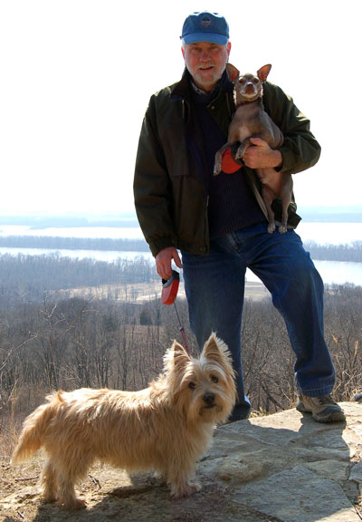 Walthall stands on a hilltop, holding one puppy with another on a leash.