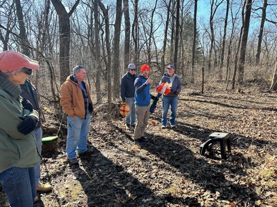 Four people in a wooded area, talking.