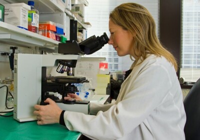 a doctor looking through a microscope in a lab