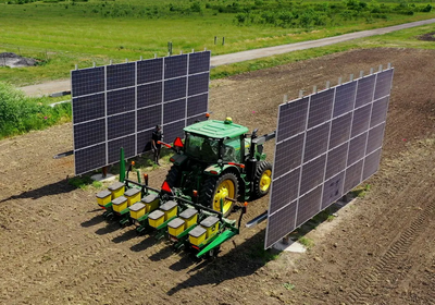 a tractor in a farm field with large solar panels attached on its sides