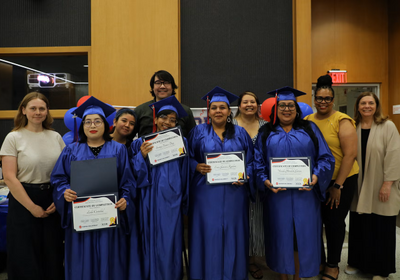 GED program graduates (in graduation gowns, left to right) Leslie Cristobal,Sunny Turner Day, Erica Garcia Aguilera and Wanda Yamileth Gomez celebrate their achievement with Center for Literacy and College of Education staff. (Photo: Lauren Covey)