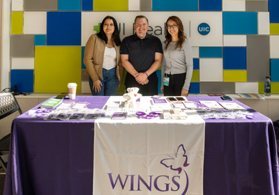 Three Wings staff members raise awareness about domestic violence while standing behind a table