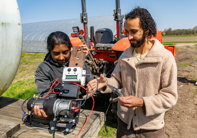 Two people working with complex machinery on a farm